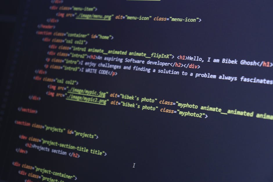 A close-up photograph of a computer screen displaying lines of HTML code, including tags such as <html>, <meta>, <title>, and <link>, with a dark background and brightly colored syntax highlighting in